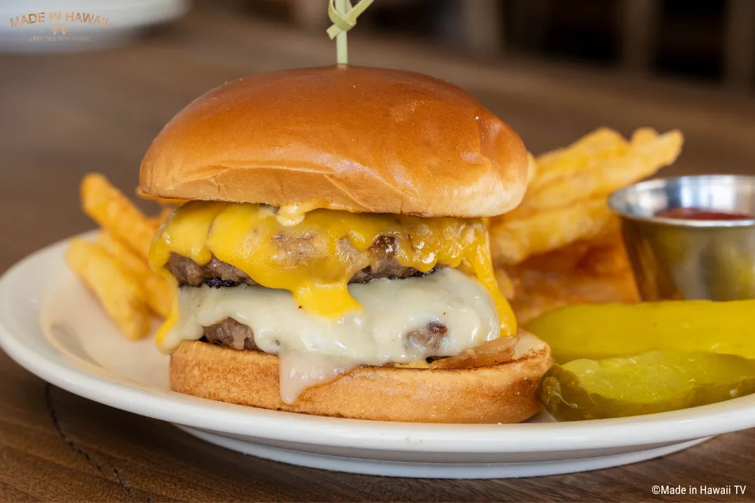 横から見たハンバーガー。チーズがとろけ、背後にはポテトフライも